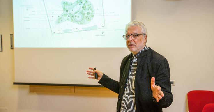 André Heller vor einer Präsentationsleinwand in einem hellen Raum mit.
